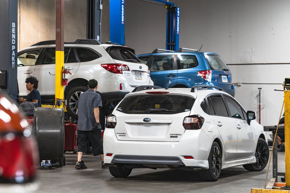 Technicians working among Subarus on lifts at our Sunbeam Ave shop